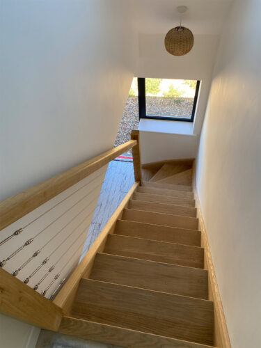 Top view of a high quality wooden staircase with a steel wire system in the handrail at a beach house in Eastbourne.