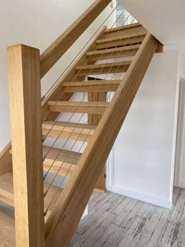 Openwork wooden stairs with the highest quality stainless steel wire installed in the handrail at Beach House in East Sussex.