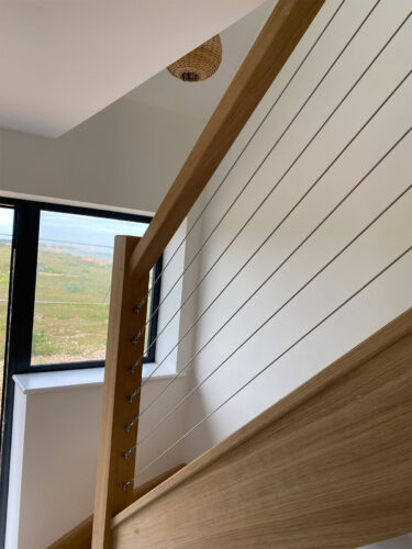 The wooden stairs with premium quality stainless steel wire mounted in balustrade at Beach House in Normans Bay, Eastbourne.
