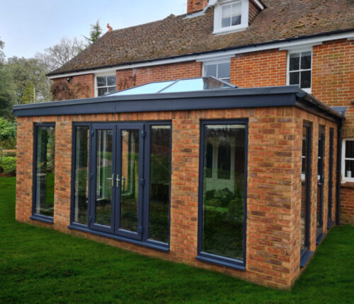 Solid construction Orangery extesnion with anthracite tall windows, lantern roof and French doors build by contractor River ODP in West Sussex