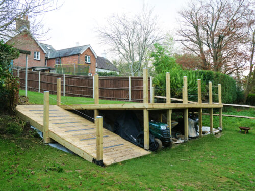 Wooden decking with posts and wire rope balustrade installed in a garden in Southwater by River.ODP installation company.