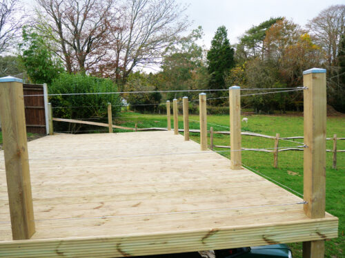 Wooden decking with posts and wire rope balustrade built in a garden in Cranleigh by River.ODP installation company.