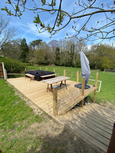 Wooden decking with timber posts and stainless steel wire rope balustrade built in a garden in Frimley by River.ODP installation company.