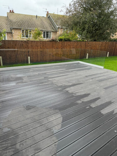 Frameless glass balustrade mounted on black composite decking in Epsom by building company River.ODP.