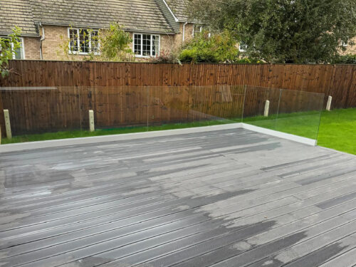 Frameless glass balustrade mounted on black composite decking in Woking by building company River.ODP.