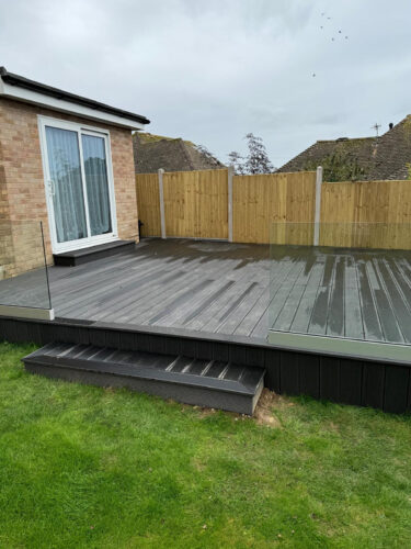 Frameless glass balustrade mounted on black composite decking in Reigate by installation company River.ODP.