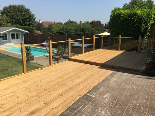 Wood and glass balustrade mounted on large timber decking in Polegate by installation company River.ODP