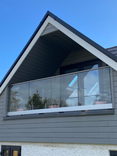 Frameless glass balustrade with steel handrail on a balcony with a minimalist design in Haslemere installed by River.ODP.