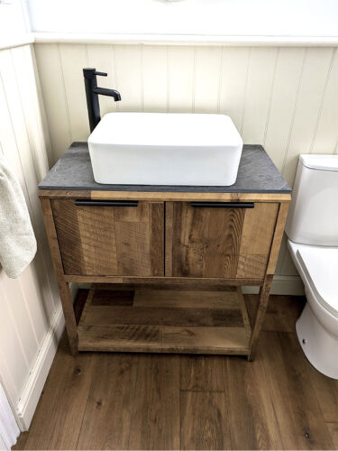 Minimalist bathroom with a wooden vanity, countertop basin, black tap