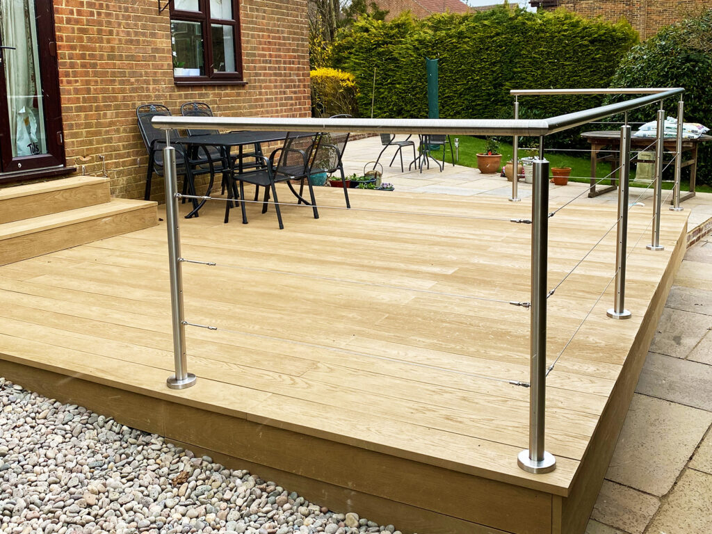 Oak colour composite decking with stainless steel wire balustrade built in Bexhill by installation company River.ODP.