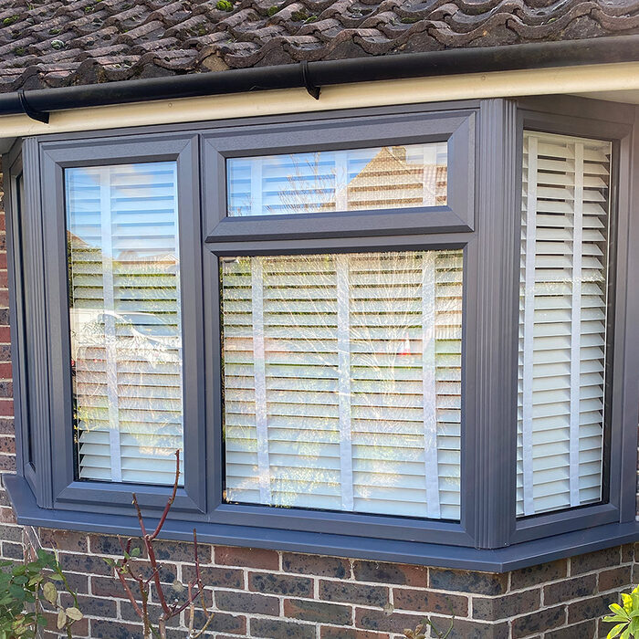 New anthracite UPVC bay window with venetian white blinds inside mounted in house in Eastbourne by builders from River.ODP.