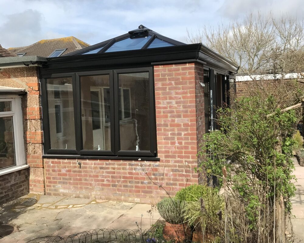 Bespoke build orangery extension in Eastbourne with big roof window and cornice / decorative fascia. Side view from garden.