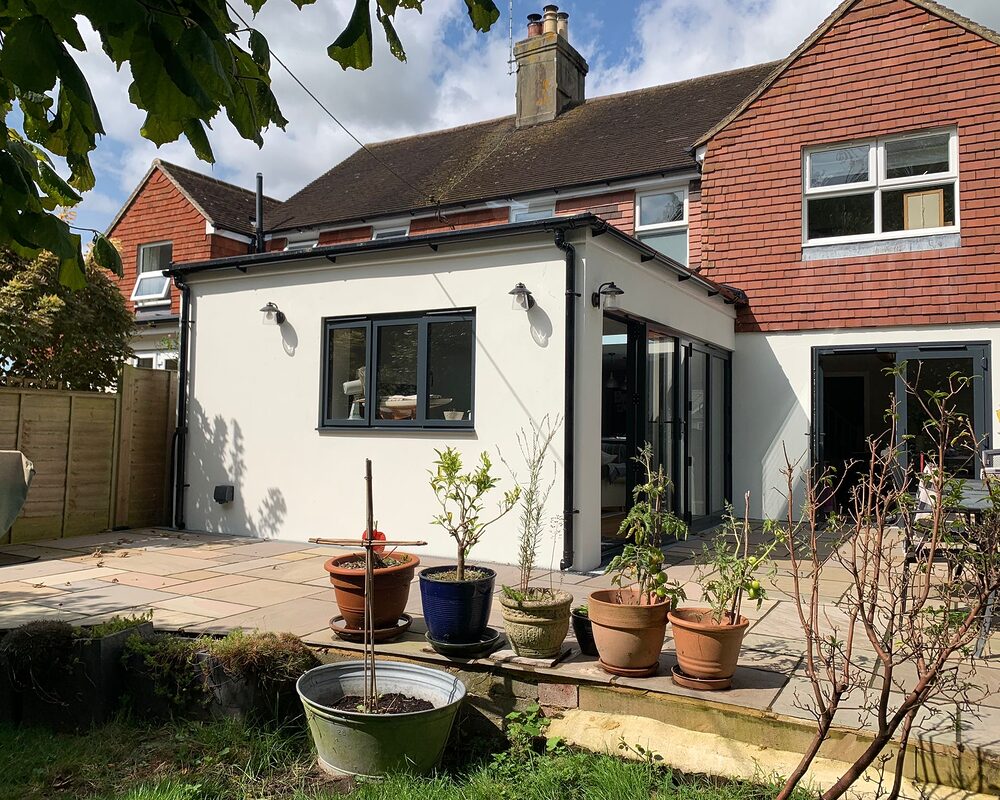 New modern house extension with bi-folding graphite aluminium doors. Corner view from the garden. by River ODP