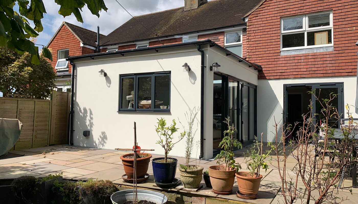 New modern house extension with bi-folding graphite aluminium doors. Corner view from the garden. by River ODP