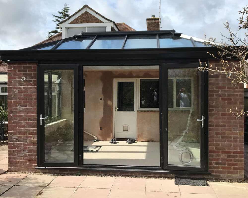 Bespoke build orangery extension in Eastbourne with big roof window and cornice / decorative fascia. French doors open into the garden.