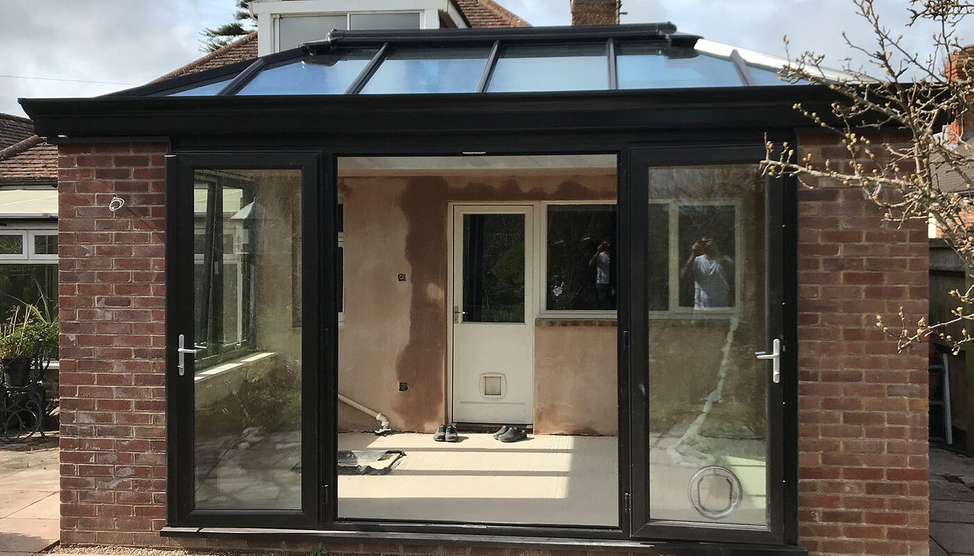 Bespoke build orangery extension in Eastbourne with big roof window and cornice / decorative fascia. French doors open into the garden.