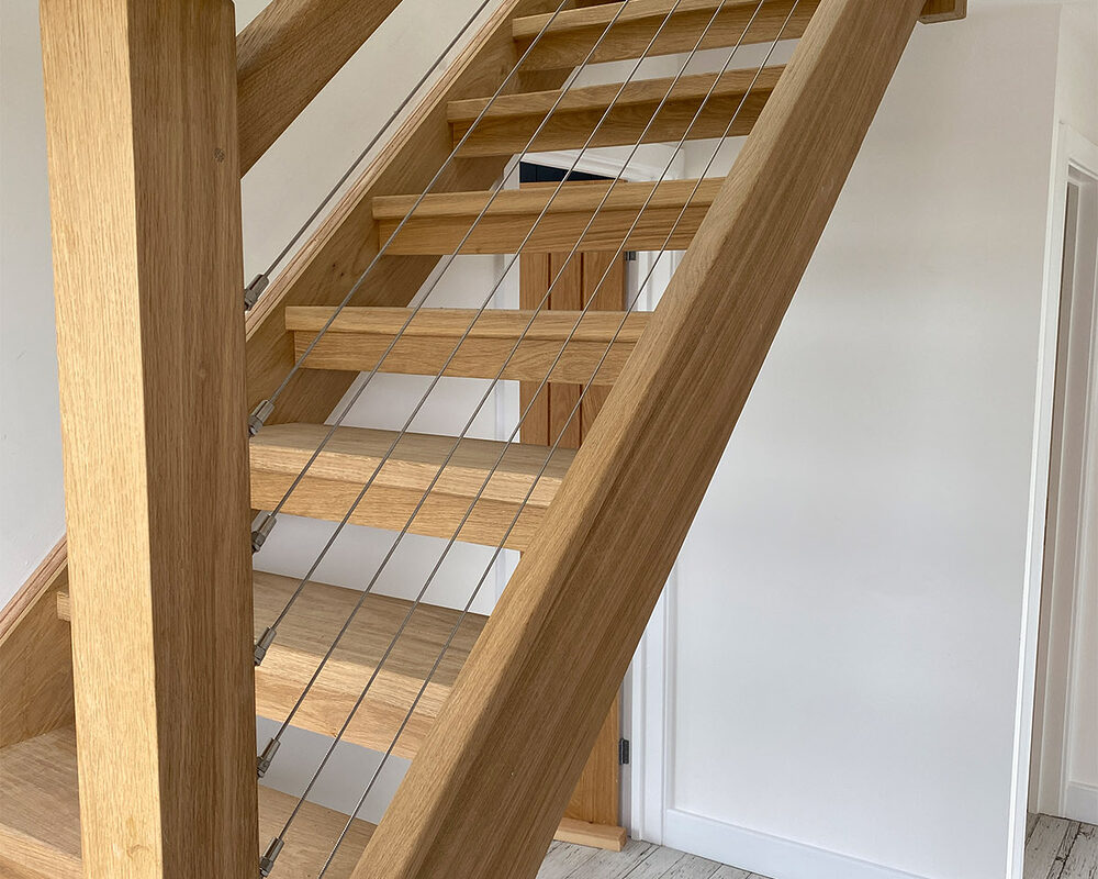 Openwork wooden stairs with the highest quality stainless steel wire installed in the handrail at Beach House in East Sussex.