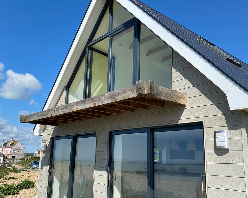 View of the back of the house with modern aluminium sliding patio doors and balcony French doors in Normans Bay in Eastbourne.