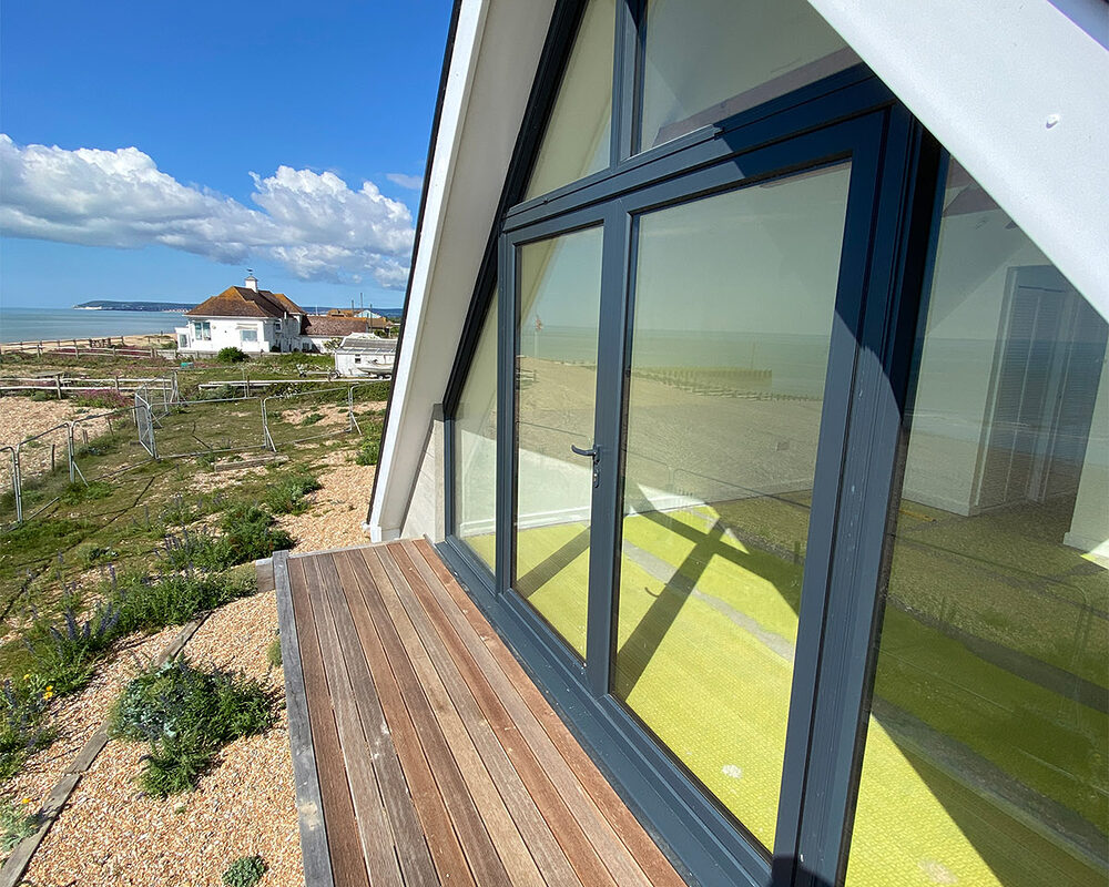 Another angle view of an aluminium anthracite window in a newly built beach house with a balcony in Normans Bay, Eastbourne.