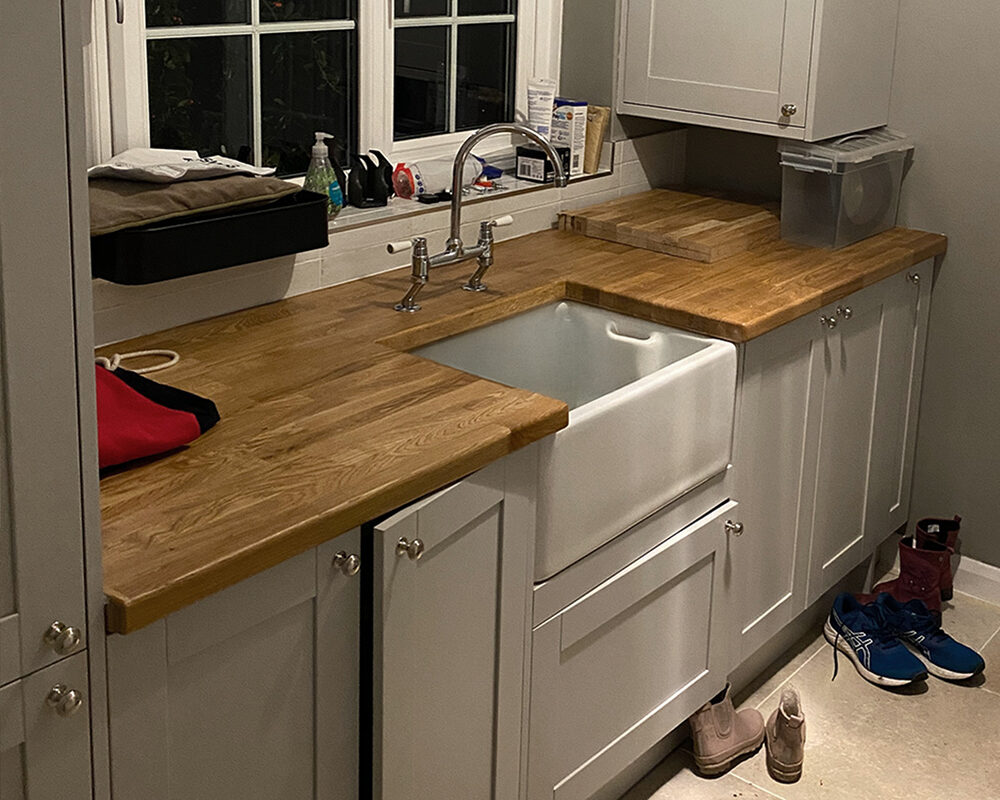 Utility room installation with wood countertops and farmhouse sink in Hastings by kitchen installers from building company River.ODP.