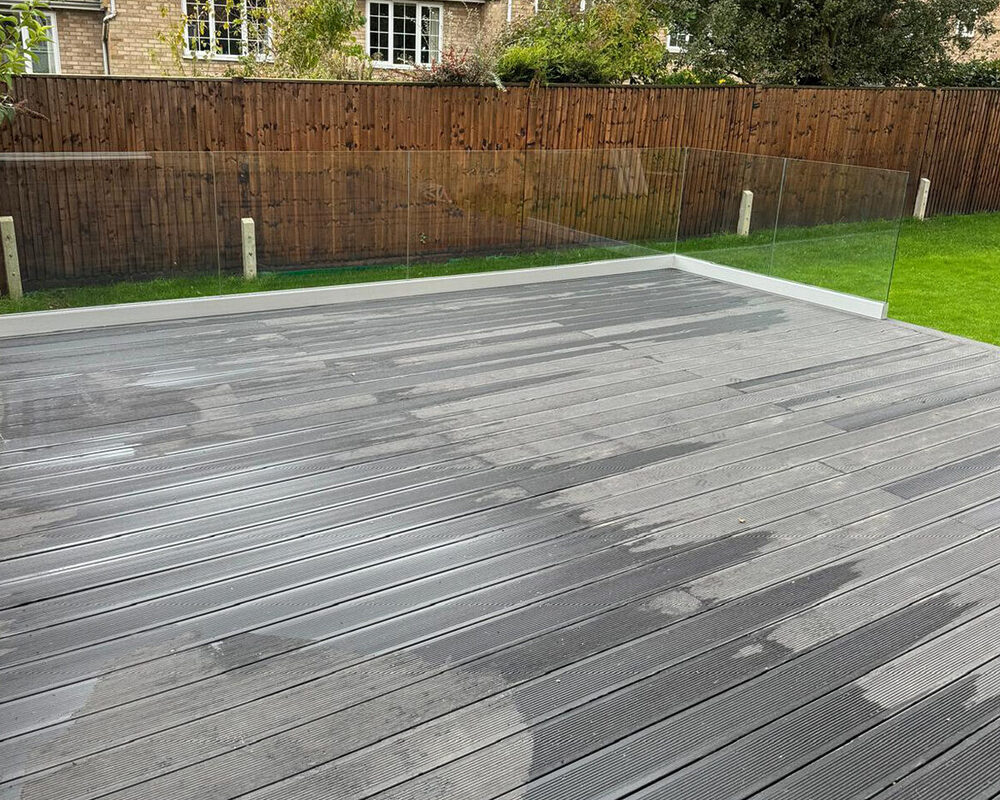 Frameless glass balustrade mounted on black composite decking in Epsom by building company River.ODP.