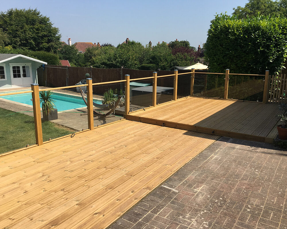 Wood and glass balustrade mounted on large timber decking in Polegate by installation company River.ODP