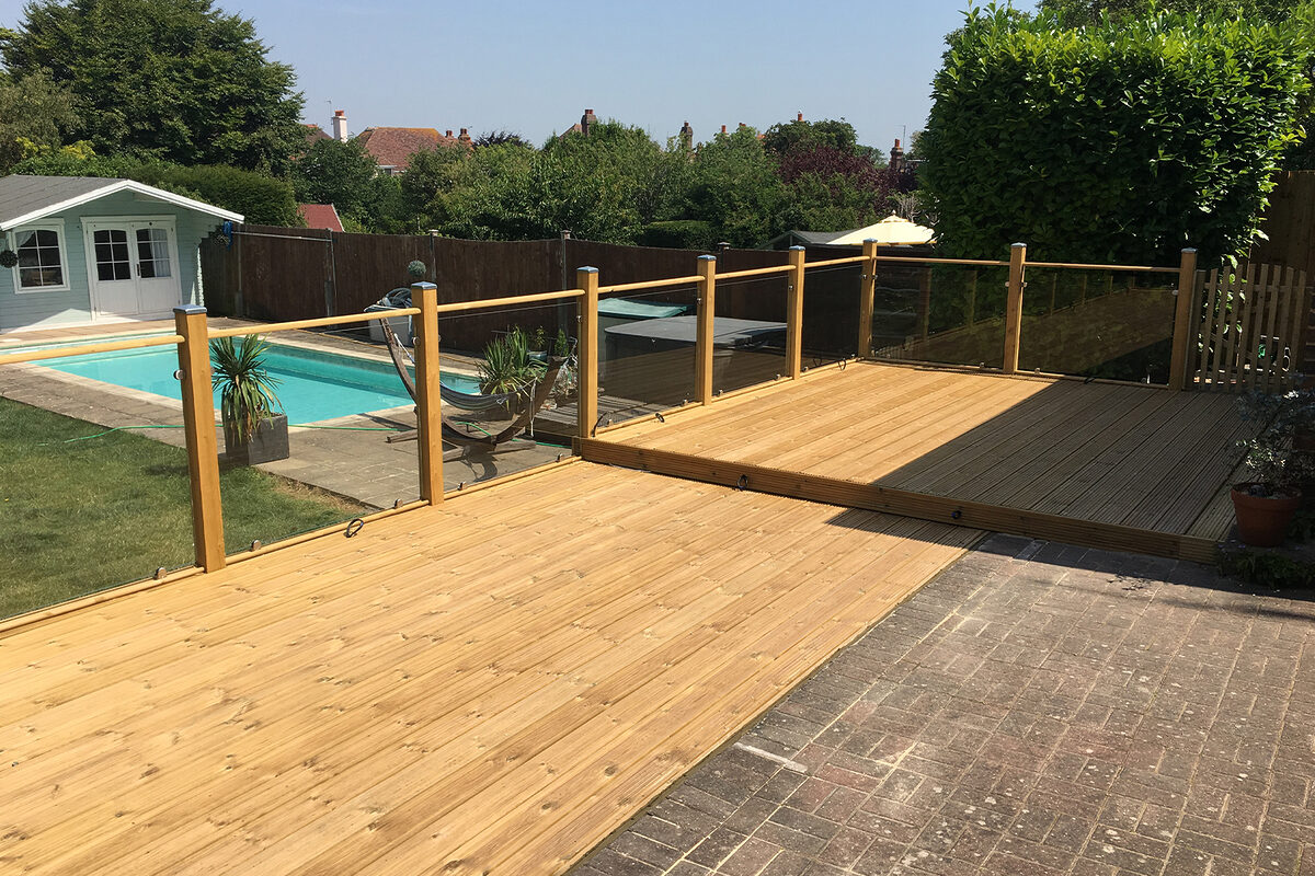 Wood and glass balustrade mounted on large timber decking in Polegate by installation company River.ODP
