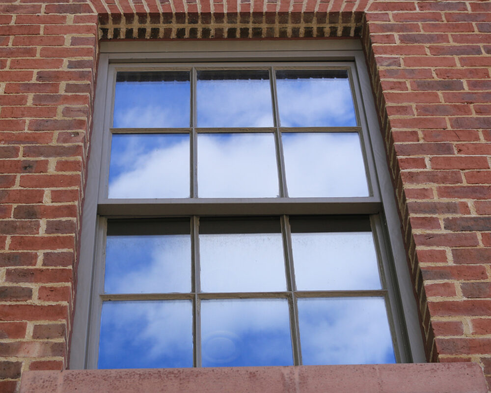 View from the outside of a brick house on a traditional brown sash window.