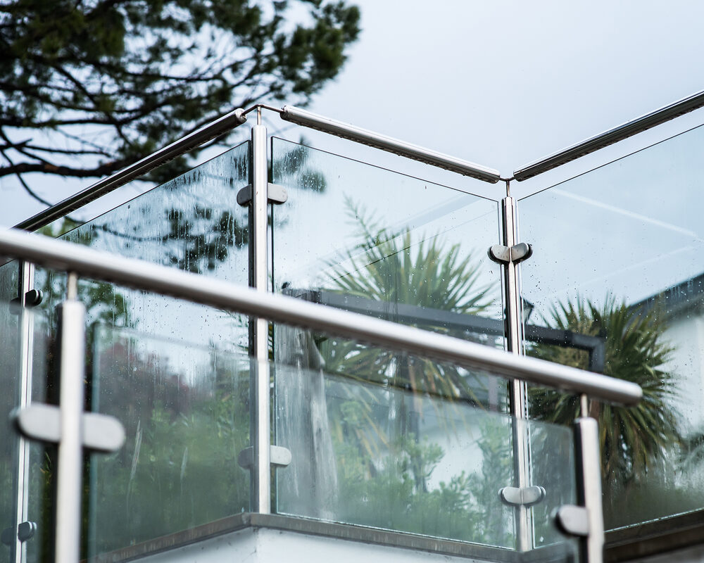 Glass balustrade with stainless steel frame & handrail installed on decking in East Sussex by construction company River.ODP