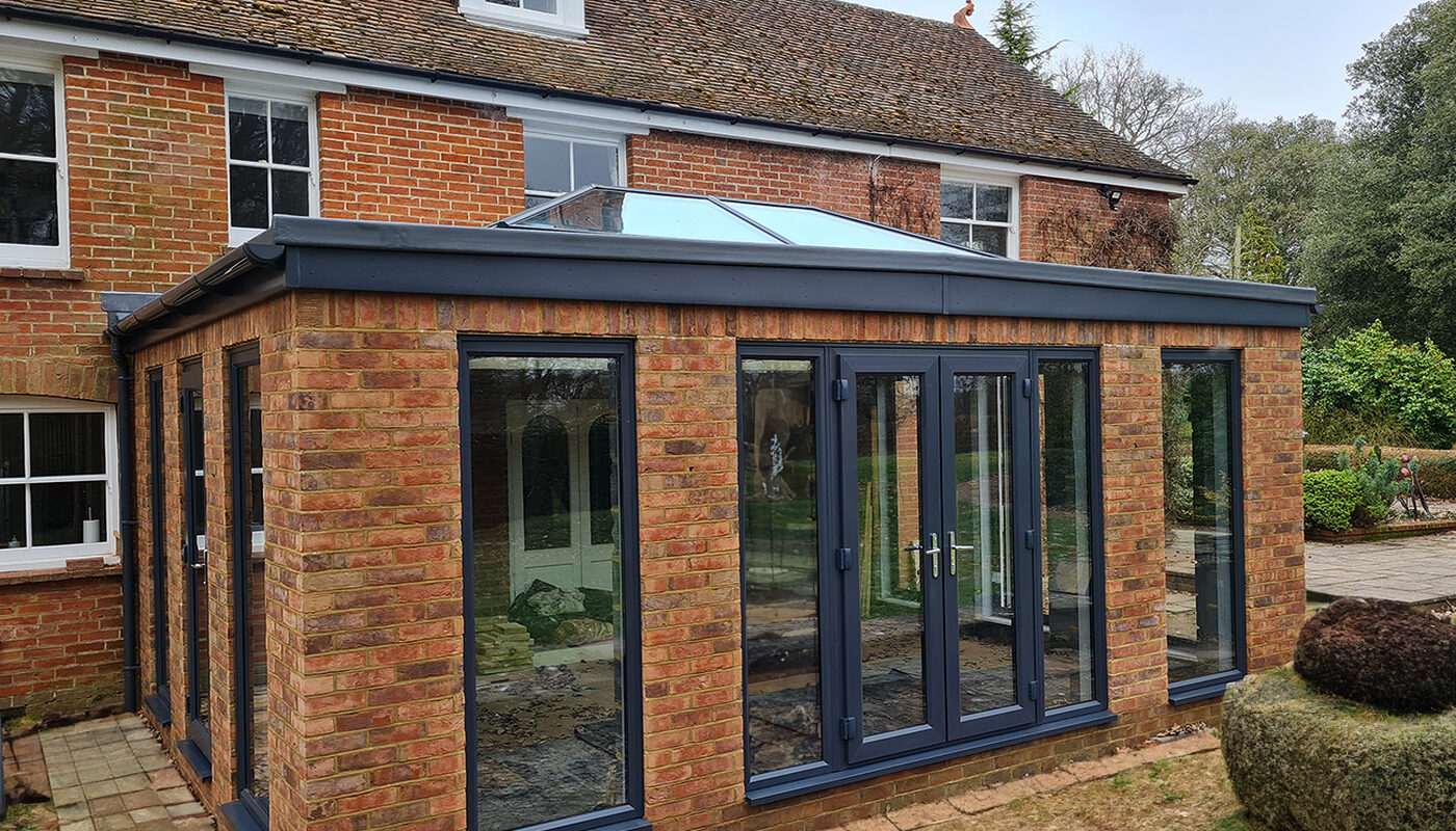 Large Orangery extension with anthracite tall windows, lantern roof and French doors build by contractor River ODP in West Sussex
