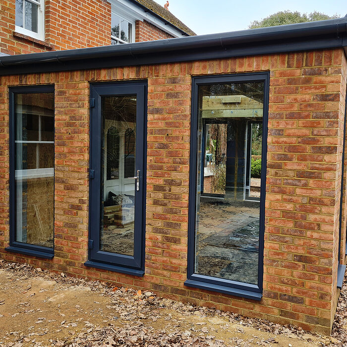 Back view of Large Orangery extension with anthracite tall windows and French doors build by contractor River ODP in West Sussex