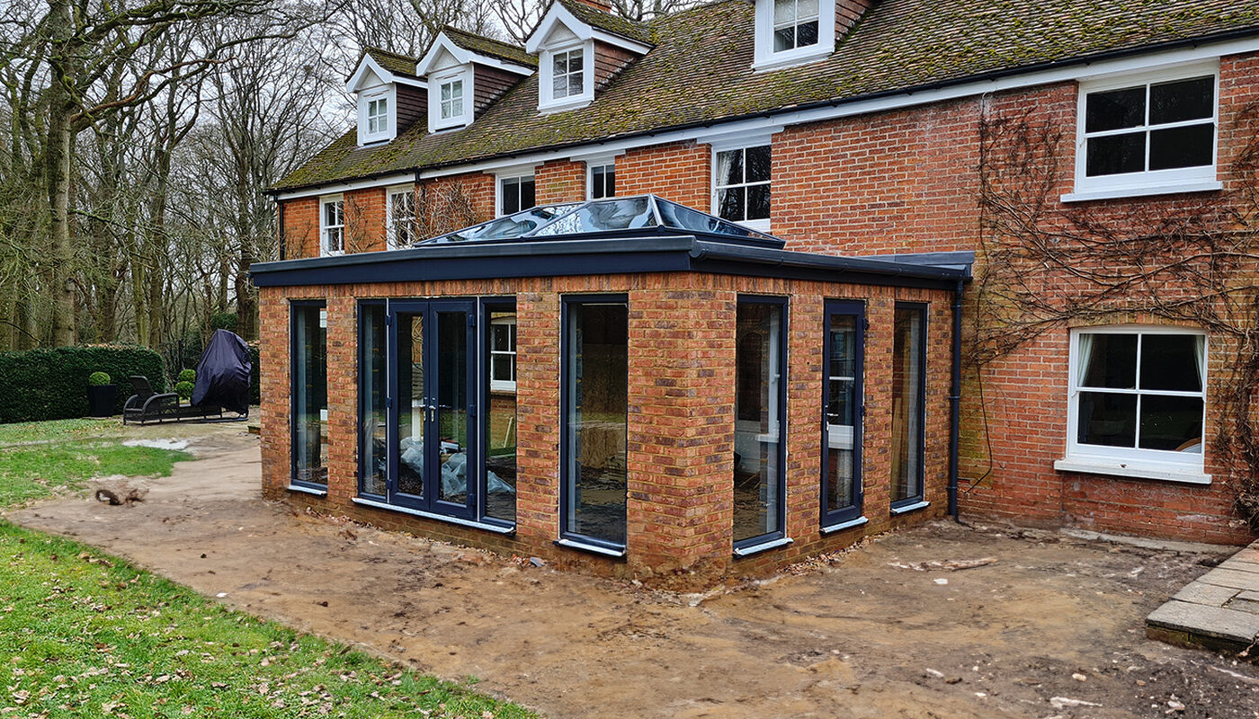 Brick Orangery extension with anthracite tall windows and French doors build by contractor River ODP in West Sussex