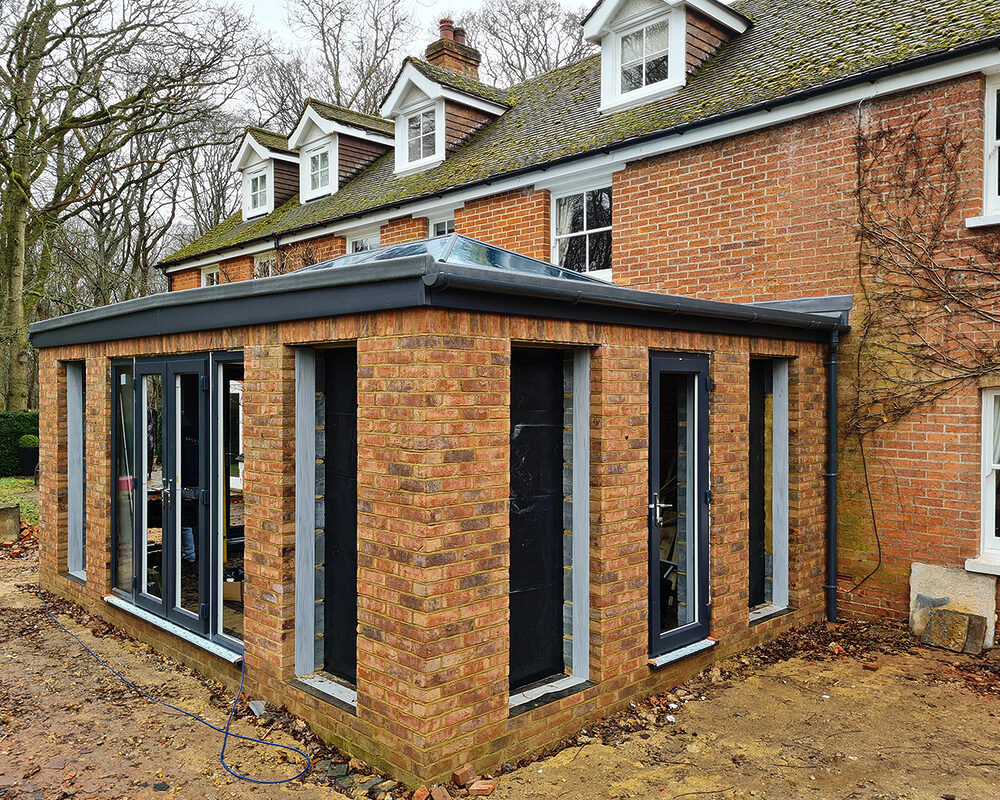 Corner view of Large Orangery extension with anthracite tall windows and French doors build by contractor River ODP in West Sussex