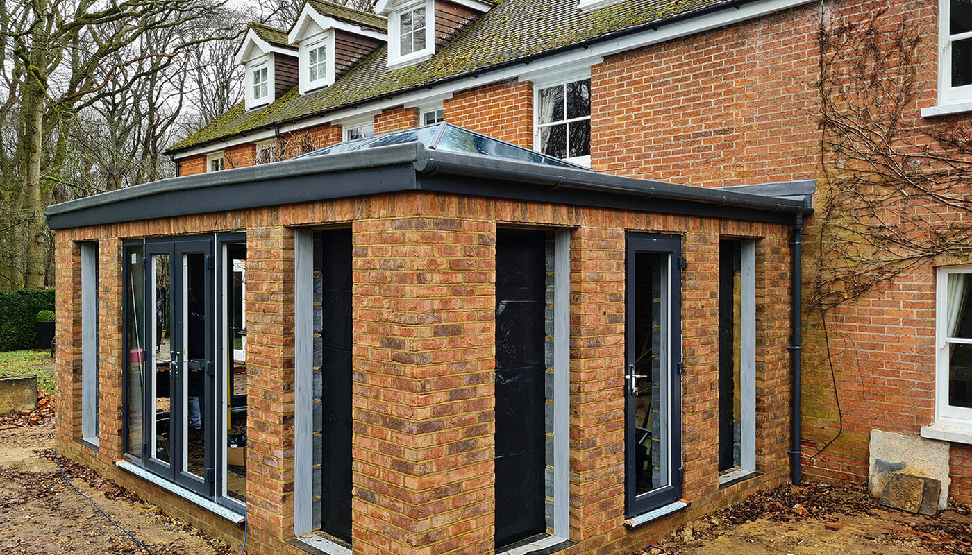 Corner view of Large Orangery extension with anthracite tall windows and French doors build by contractor River ODP in West Sussex