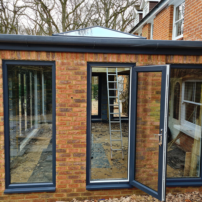 Side view of Large Orangery with anthracite tall windows and French doors build by contractor River ODP in West Sussex
