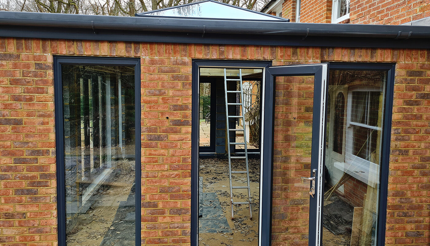 Side view of Large Orangery with anthracite tall windows and French doors build by contractor River ODP in West Sussex
