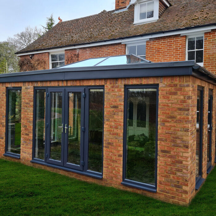 Solid construction Orangery extesnion with anthracite tall windows, lantern roof and French doors build by contractor River ODP in West Sussex