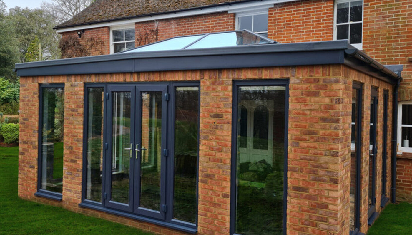 Solid construction Orangery extesnion with anthracite tall windows, lantern roof and French doors build by contractor River ODP in West Sussex